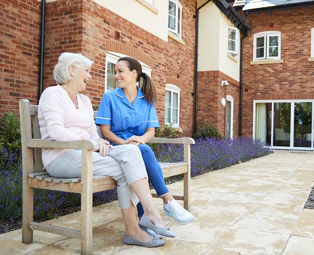 Caregiver assisting an elderly resident with a tablet-based medication administration record
